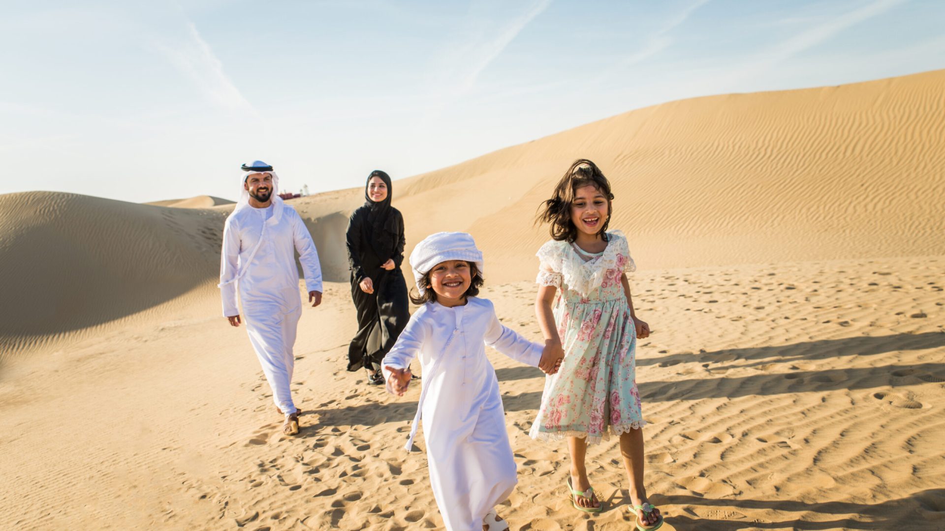 Arabian family with kids having fun in the desert - Parents and children celebrating holiday in the Dubai desrt