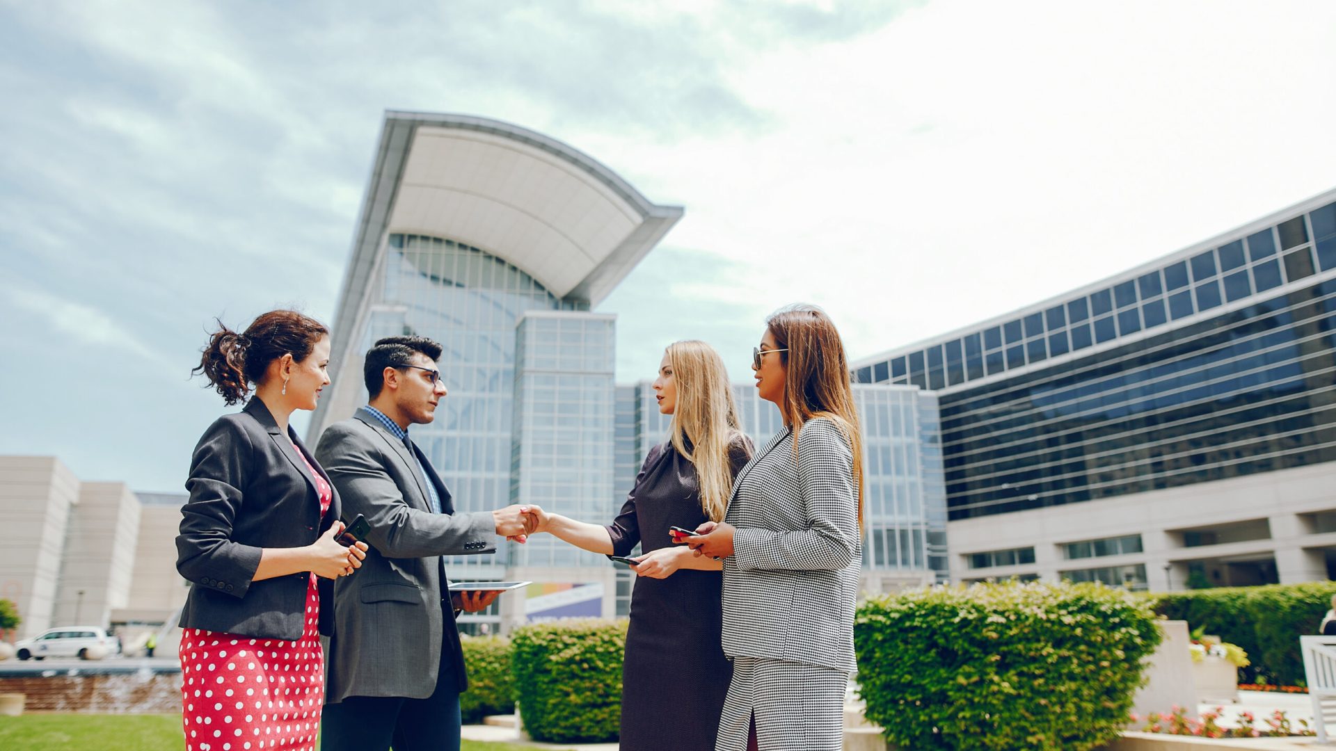 Handsome businessman in a city. Businessman in a glasses. Business partners in a summer city. Man and three women standingin a sity with tablet and phones
