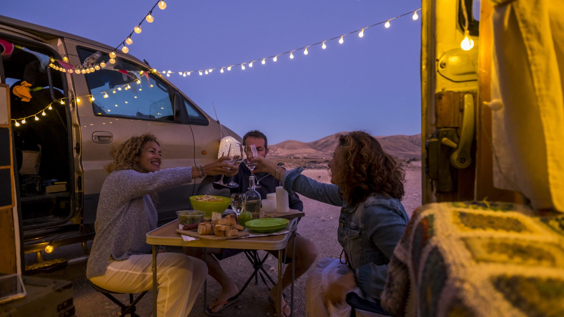 Group of cheerful happy and free people friends celebrate together toasting in outdoor adventure van vehicle travel vacation - enjoy free lifestyle adult man and women in friendship