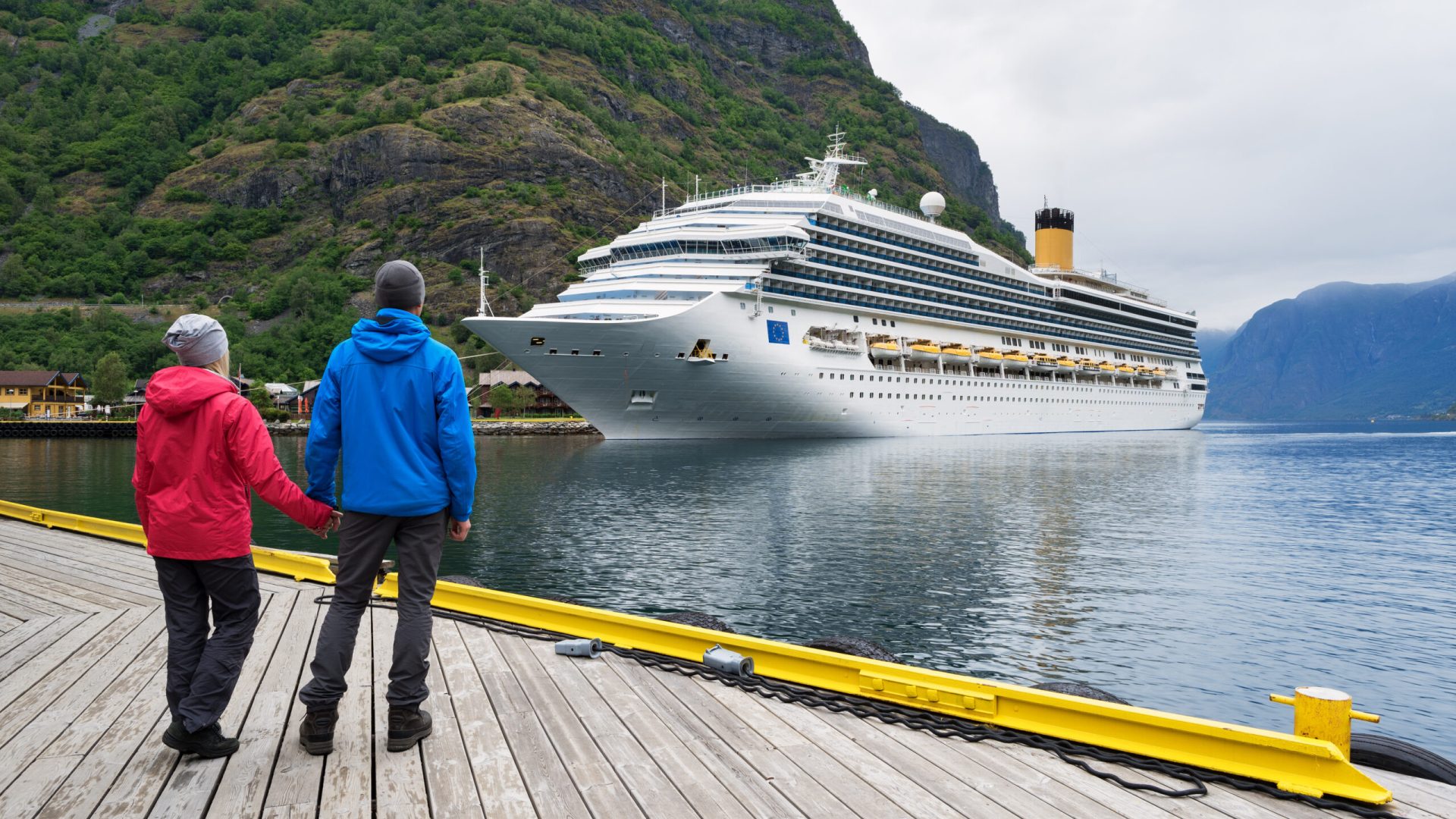 Couple of travelers look at the Cruise liner. Fjord Aurlandsfjord near Flam village, Norway