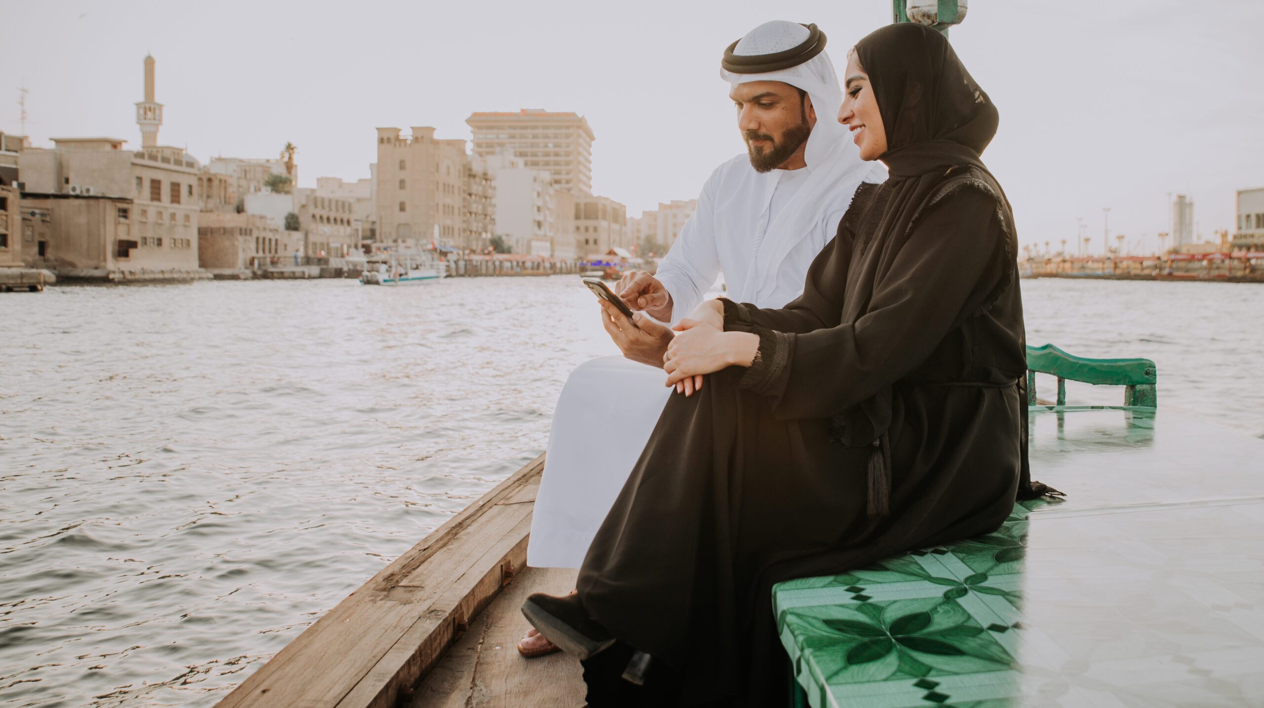 Happy couple spending time in Dubai. man and woman wearing traditional clothes taking a cruise on the river