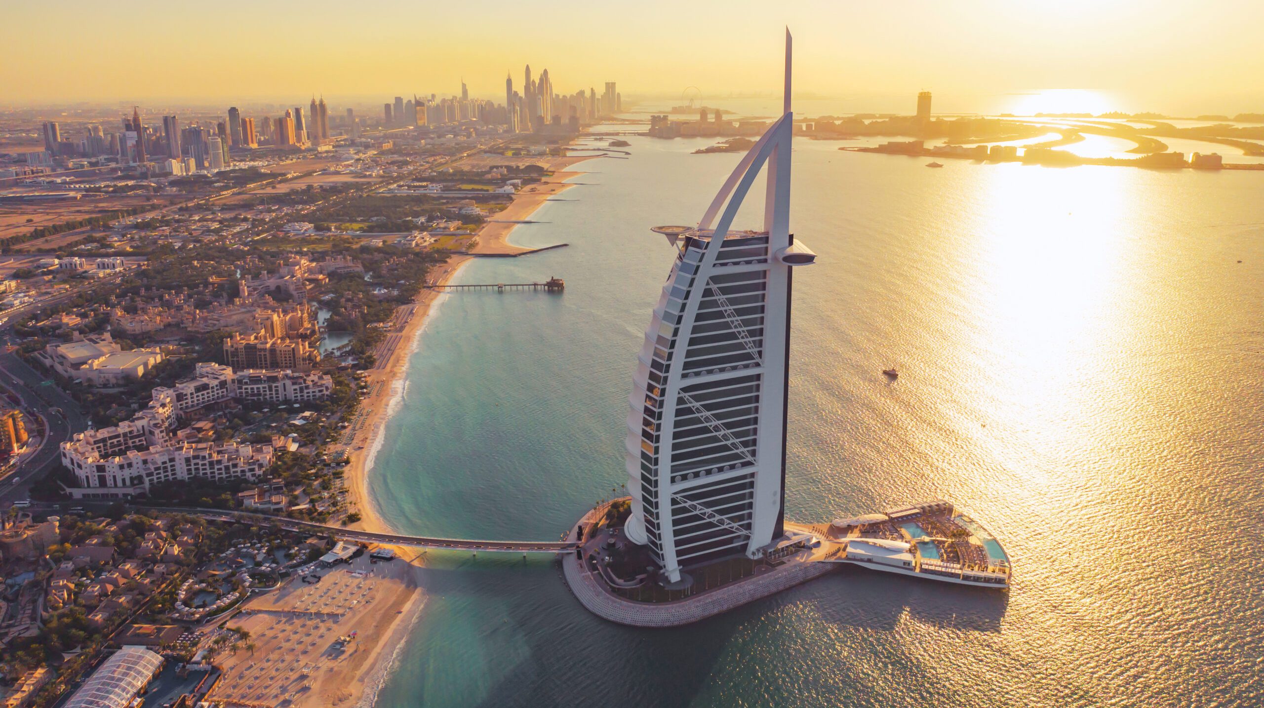 Aerial view of Burj Al Arab Jumeirah Island or boat building, Dubai Downtown skyline, United Arab Emirates or UAE. Financial district in urban city. Skyscrapers at sunset.
