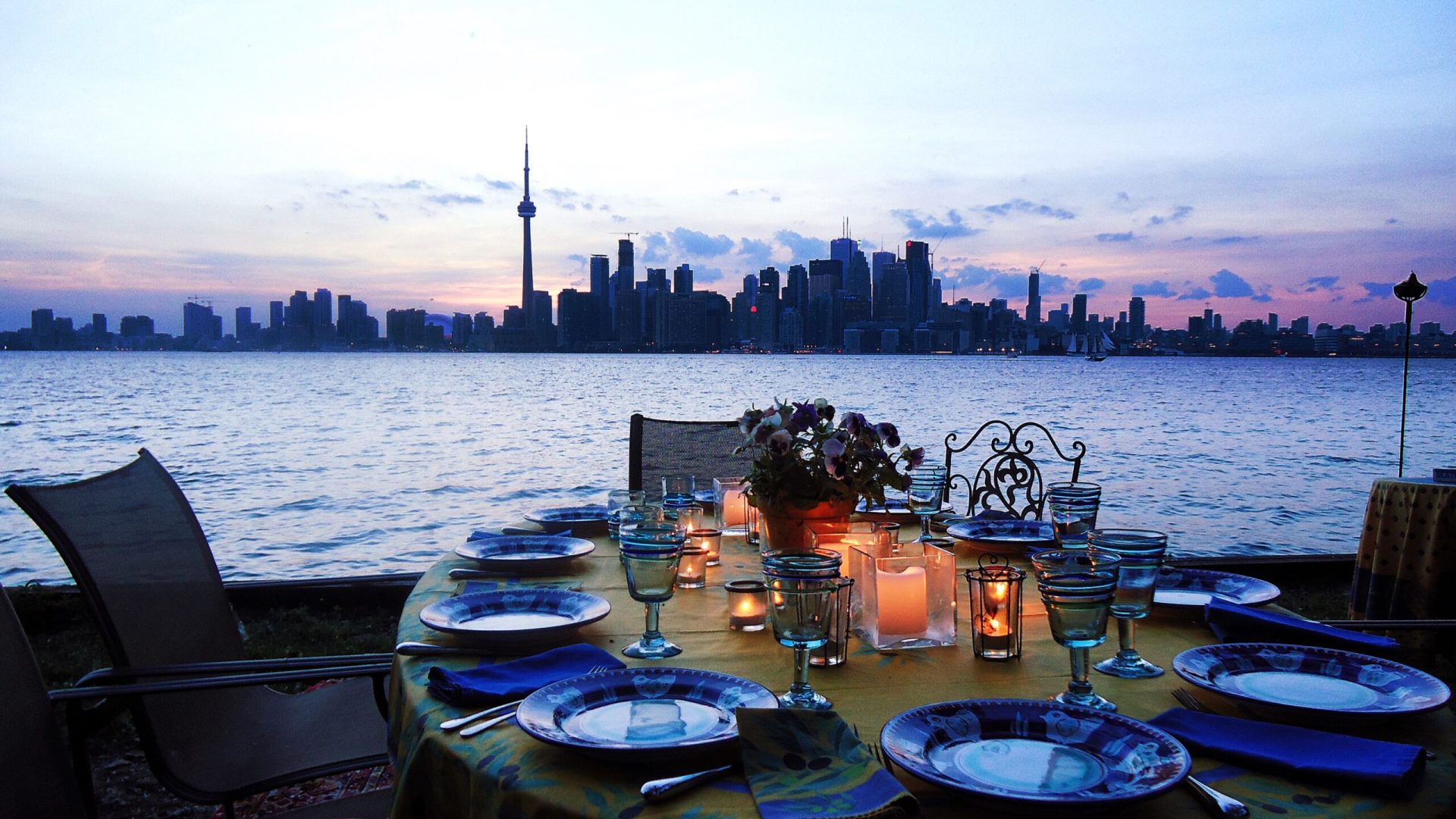 empty-plates-arranged-table-by-river-against-cityscape