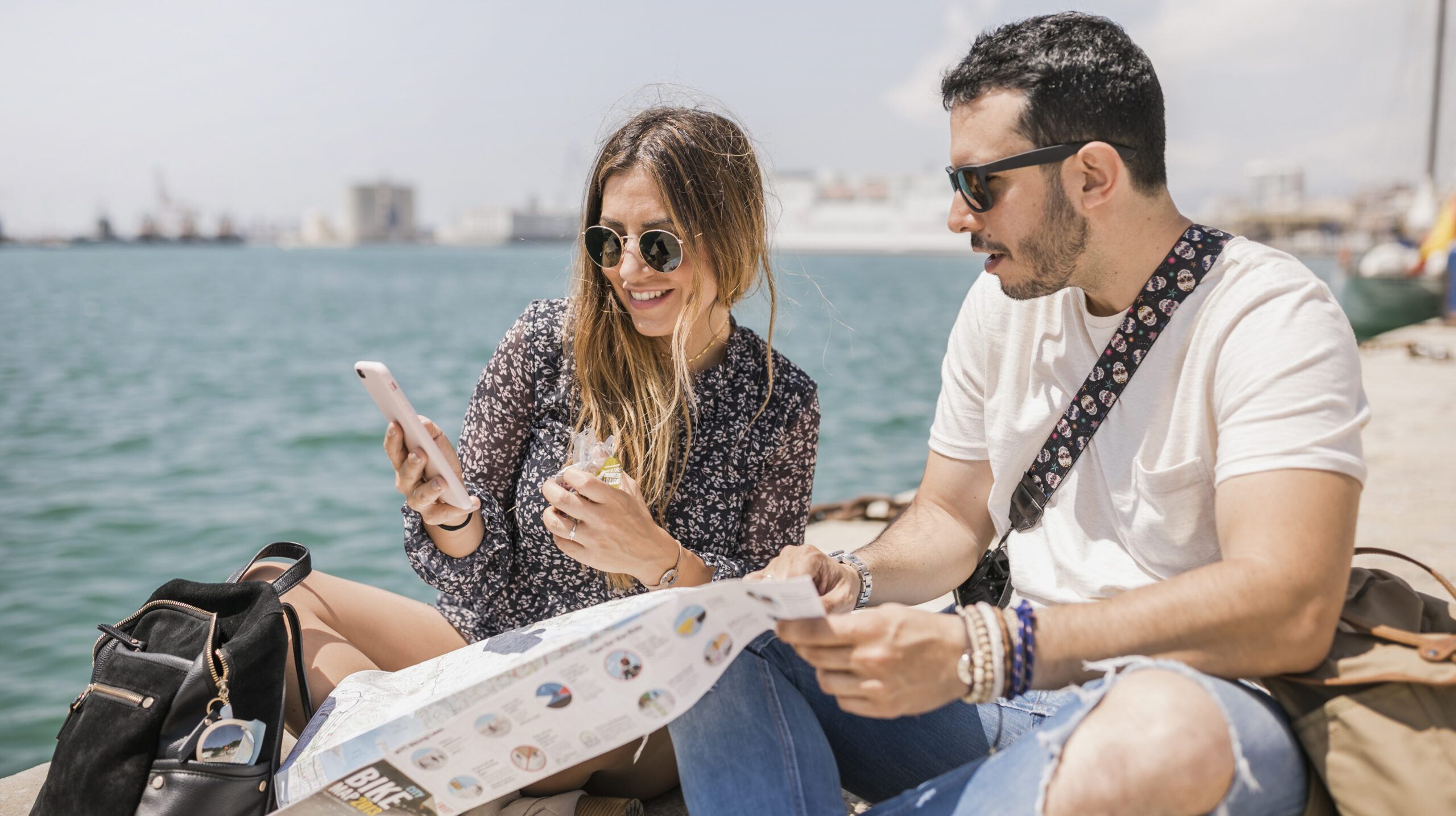female-tourist-showing-her-boyfriend-cell-phone-sitting-jetty