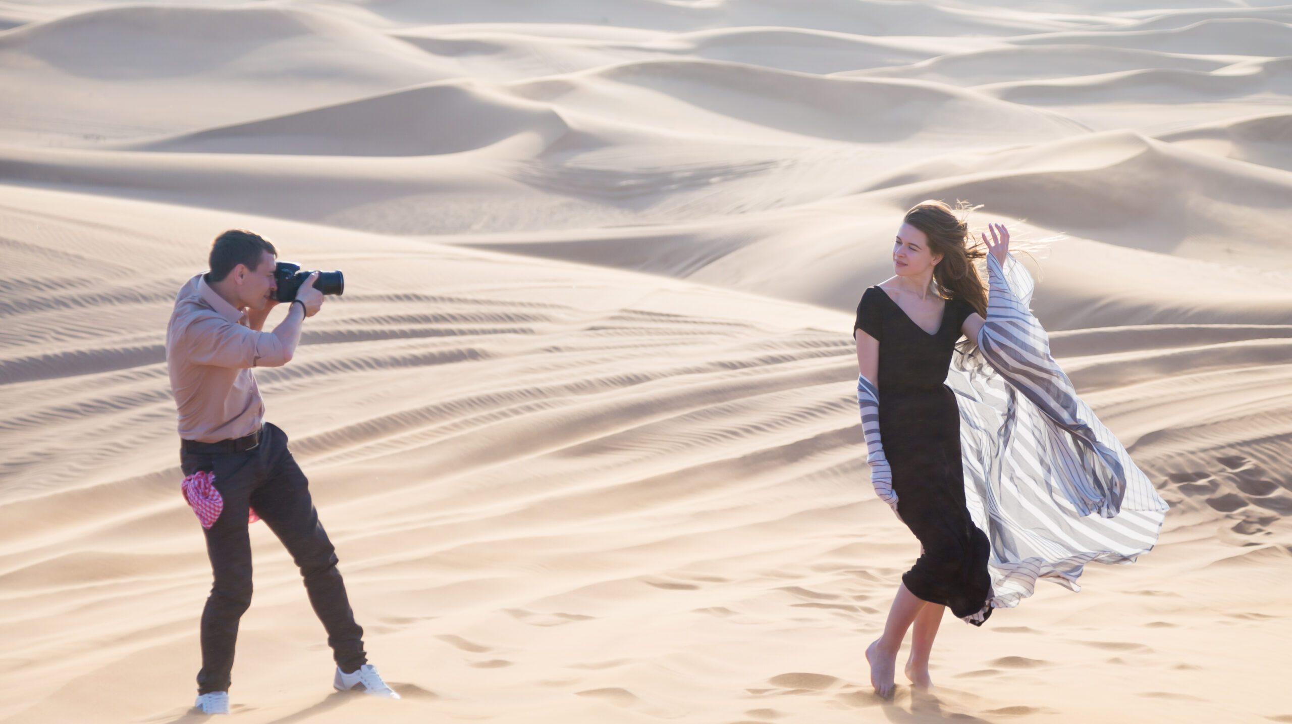 A photographer works with a girl model in extreme desert conditions.