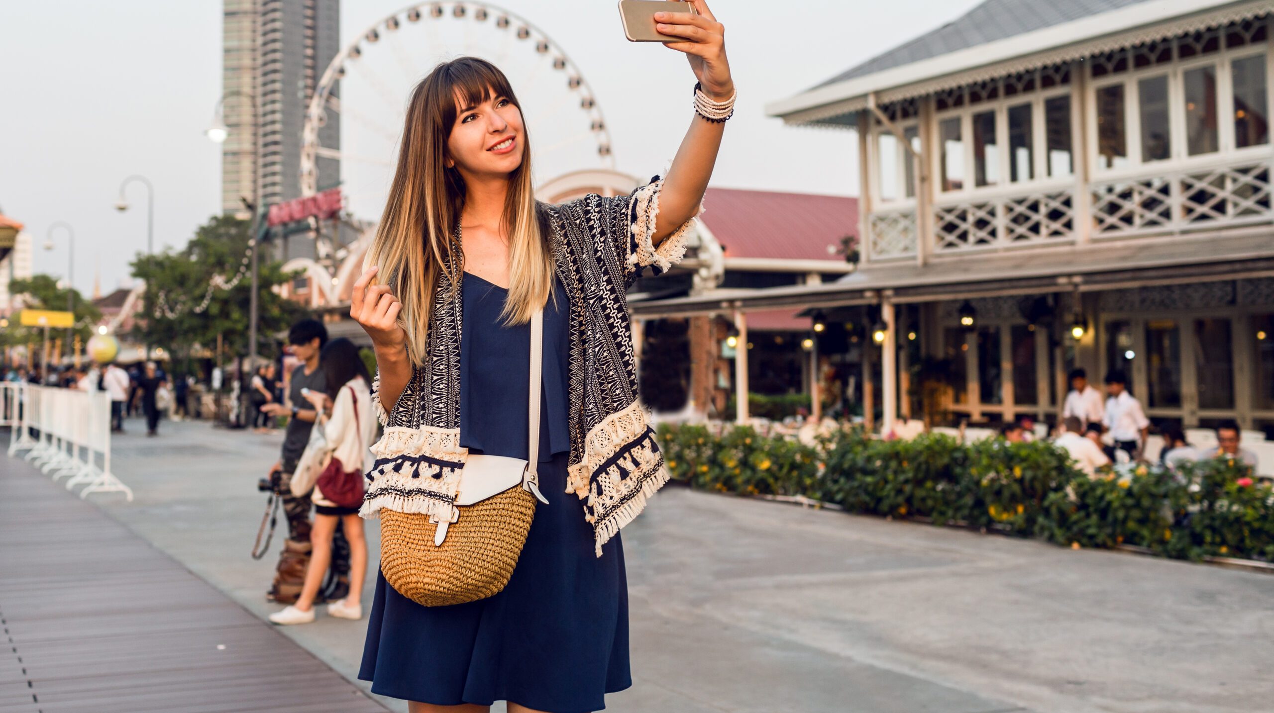 Happy woman making self portrait  on ferris wheel background, walking on  riverfront.  Pretty tourist girl enjoying sights , having great time in Bangkok.