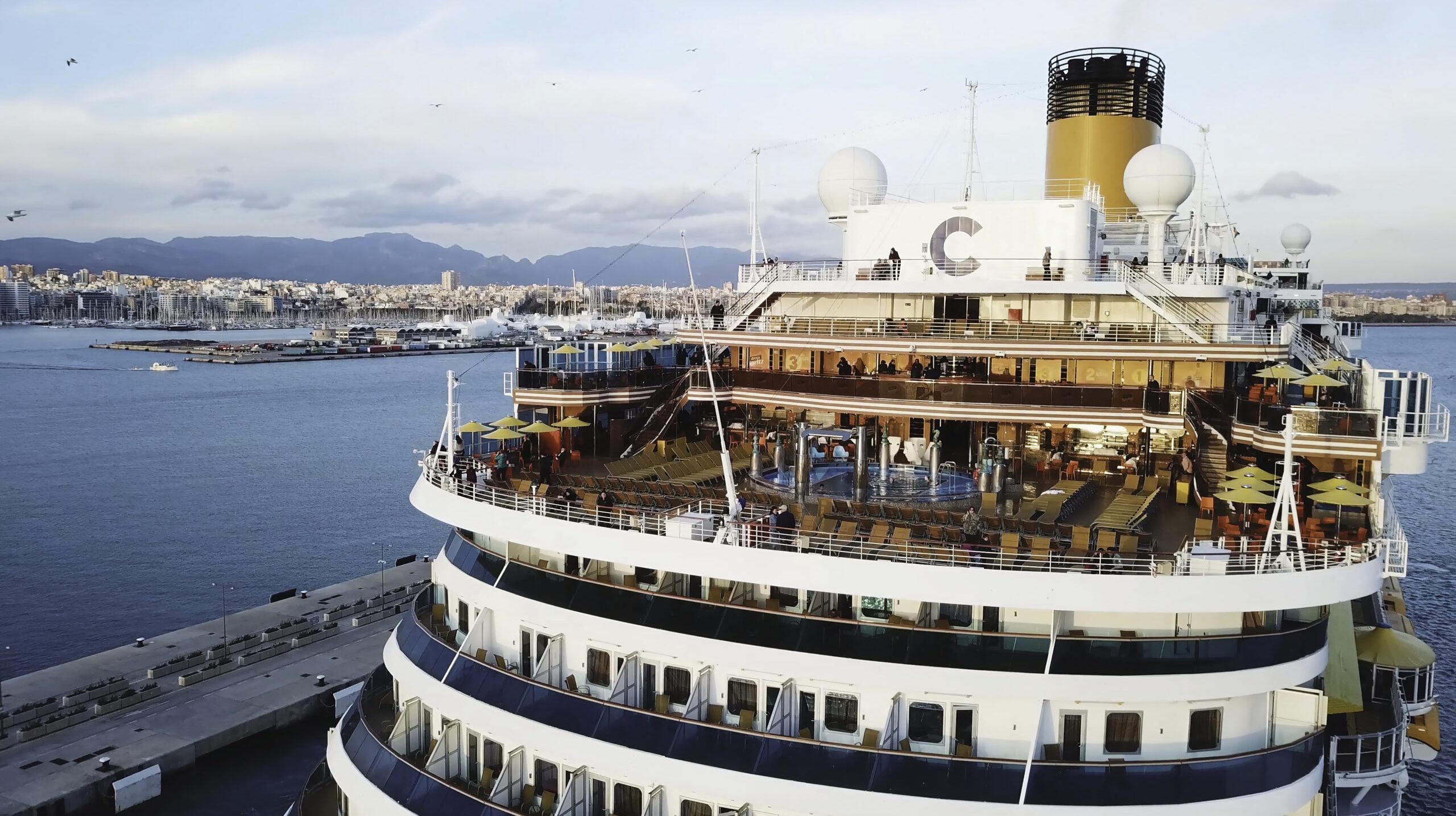 Large Cruise ship sailing across sea near the harbor. Stock. Top view of a huge cruise ship in the sea. Summer vacation concept, travel by water around the world.
