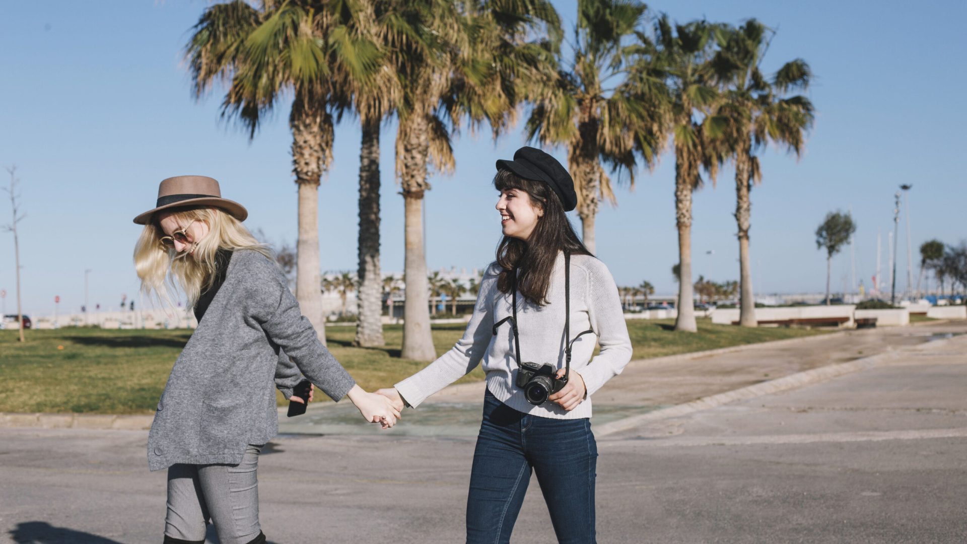 laughing-girls-holding-hands-strolling-sunlight
