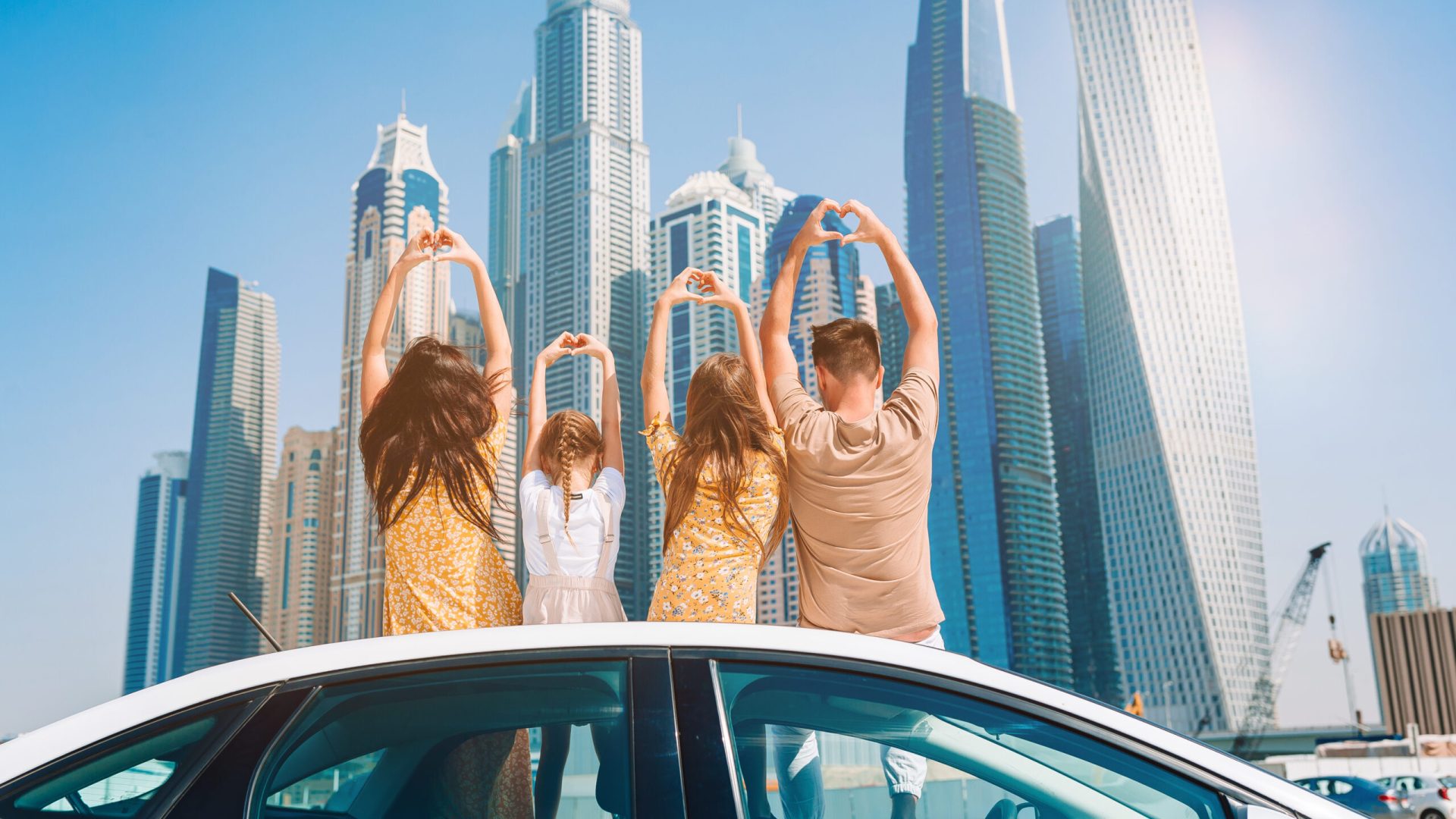 Family vacation. Family of four on car vacation on background of skyscrapers in Dubai
