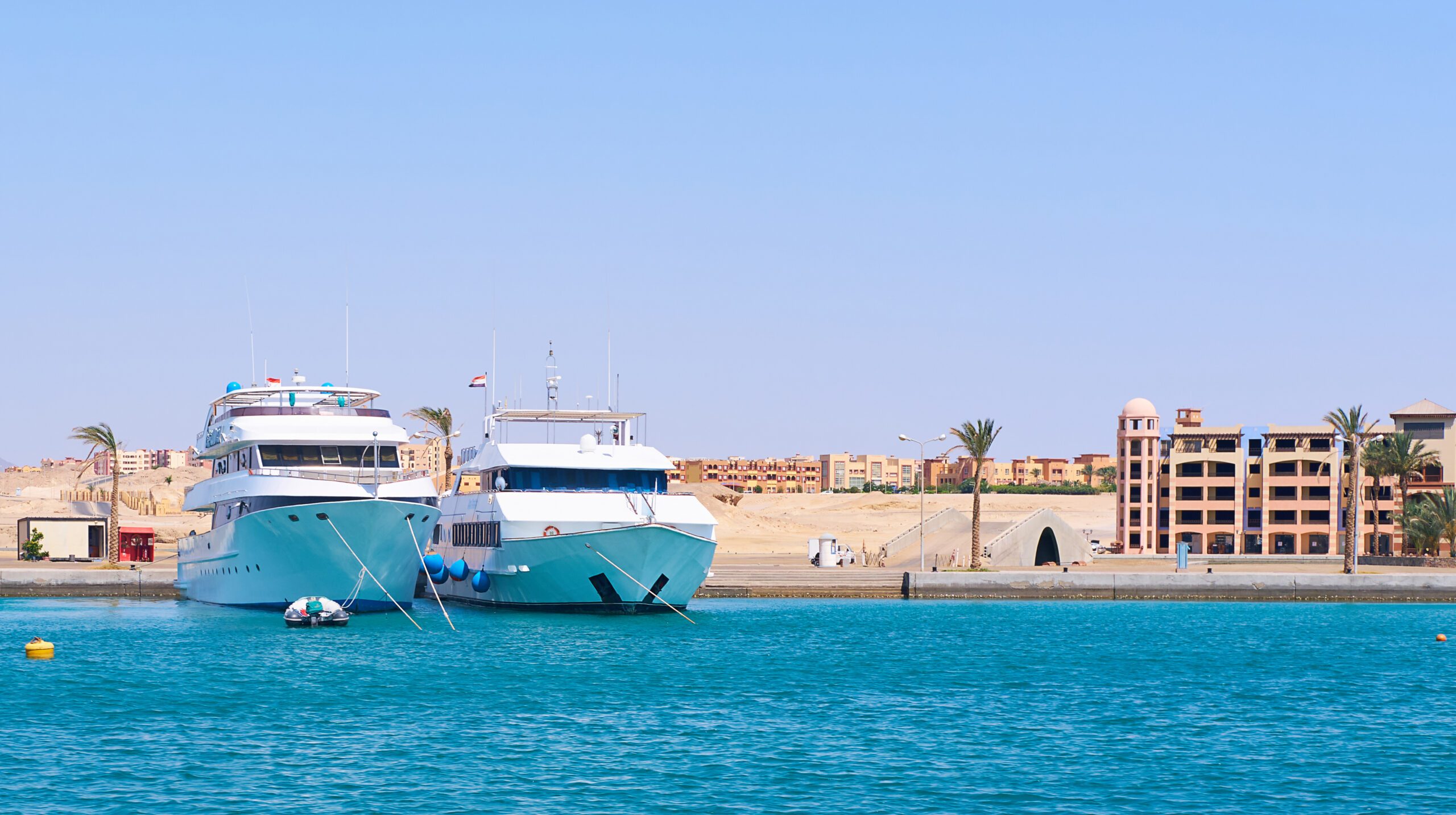 Luxury Yachts Docked at Tropical Resort Marina, Clear Blue Sea and Sky.