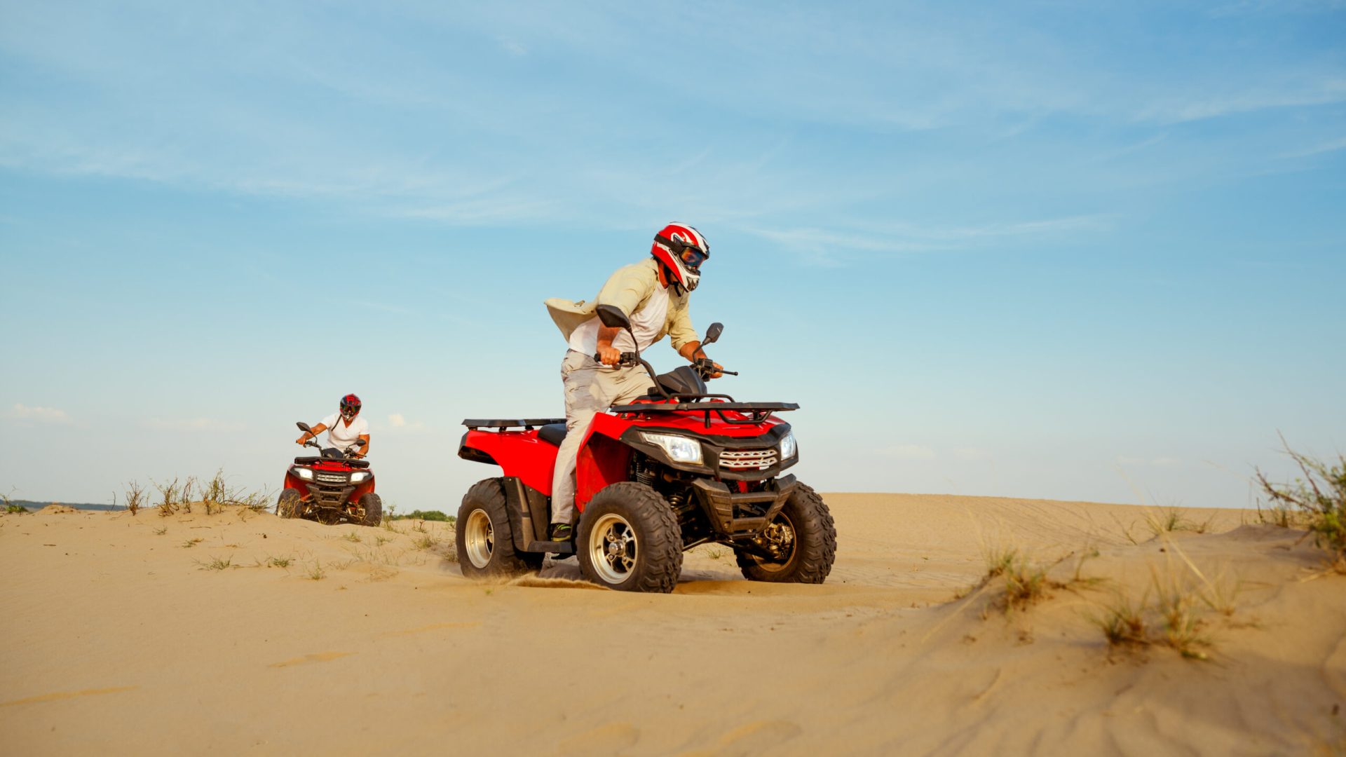 Man in helmet rides on atv in desert sands. Male person on quad bike, sandy race, dune safari in hot sunny day, 4x4 extreme adventure, quad-biking