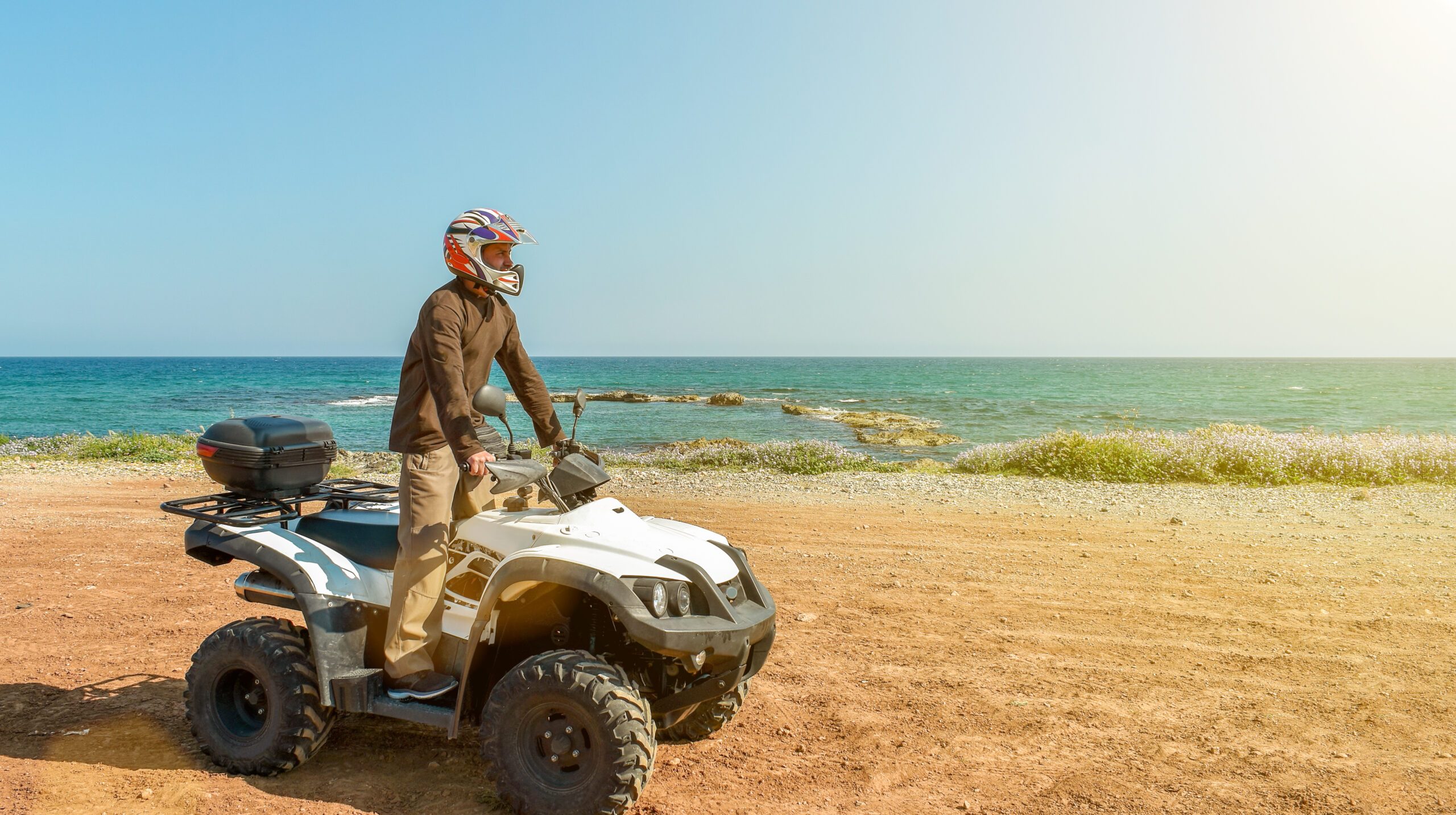 A man is driving ATV on off-road. Sunny.