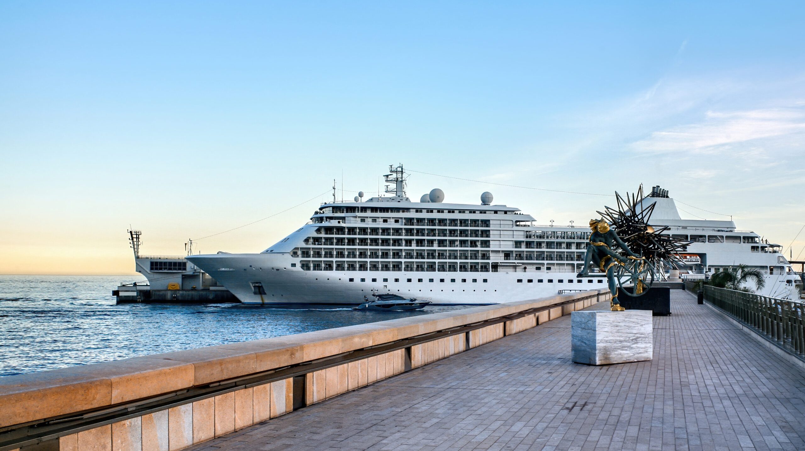 Moored cruise ship in the Monaco seaport with sculptures on the pier