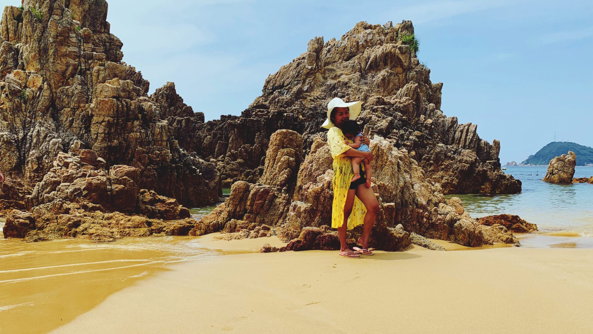 mother-with-boy-standing-by-rock-against-sky