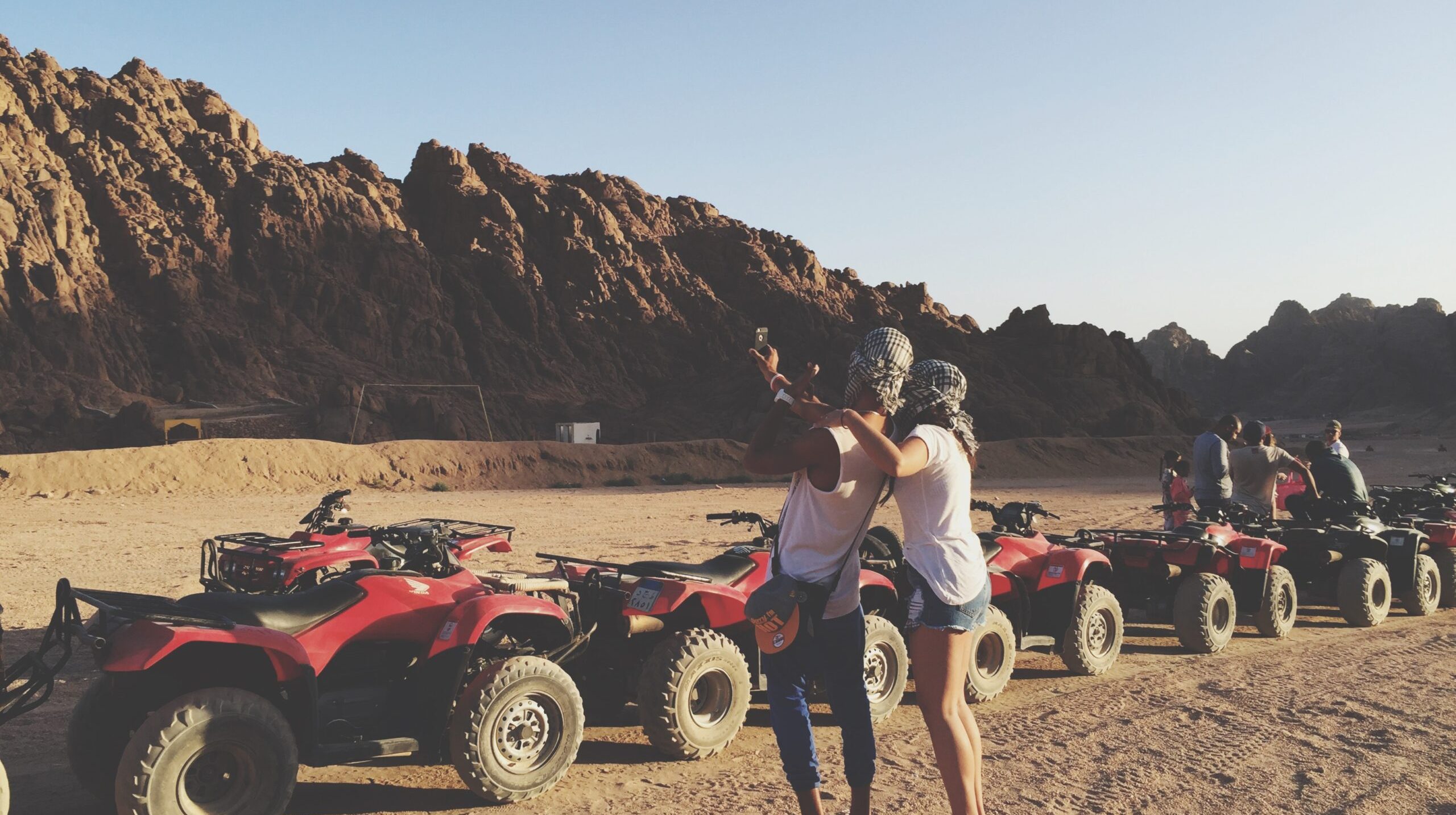 people-desert-standing-by-quadbikes-against-clear-sky