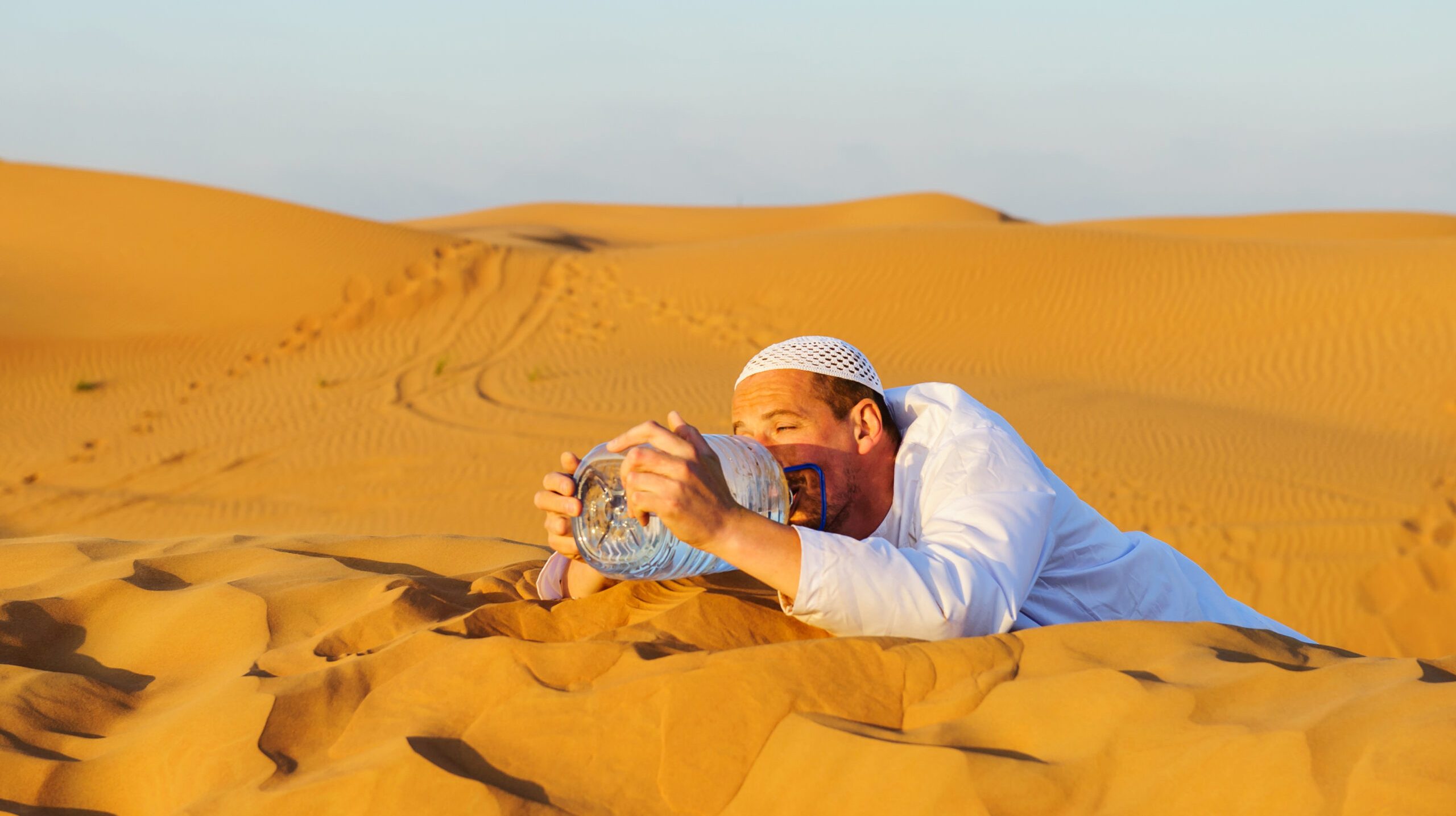 Portrait of thirsty Arabic man on a middle of yellow desert.
