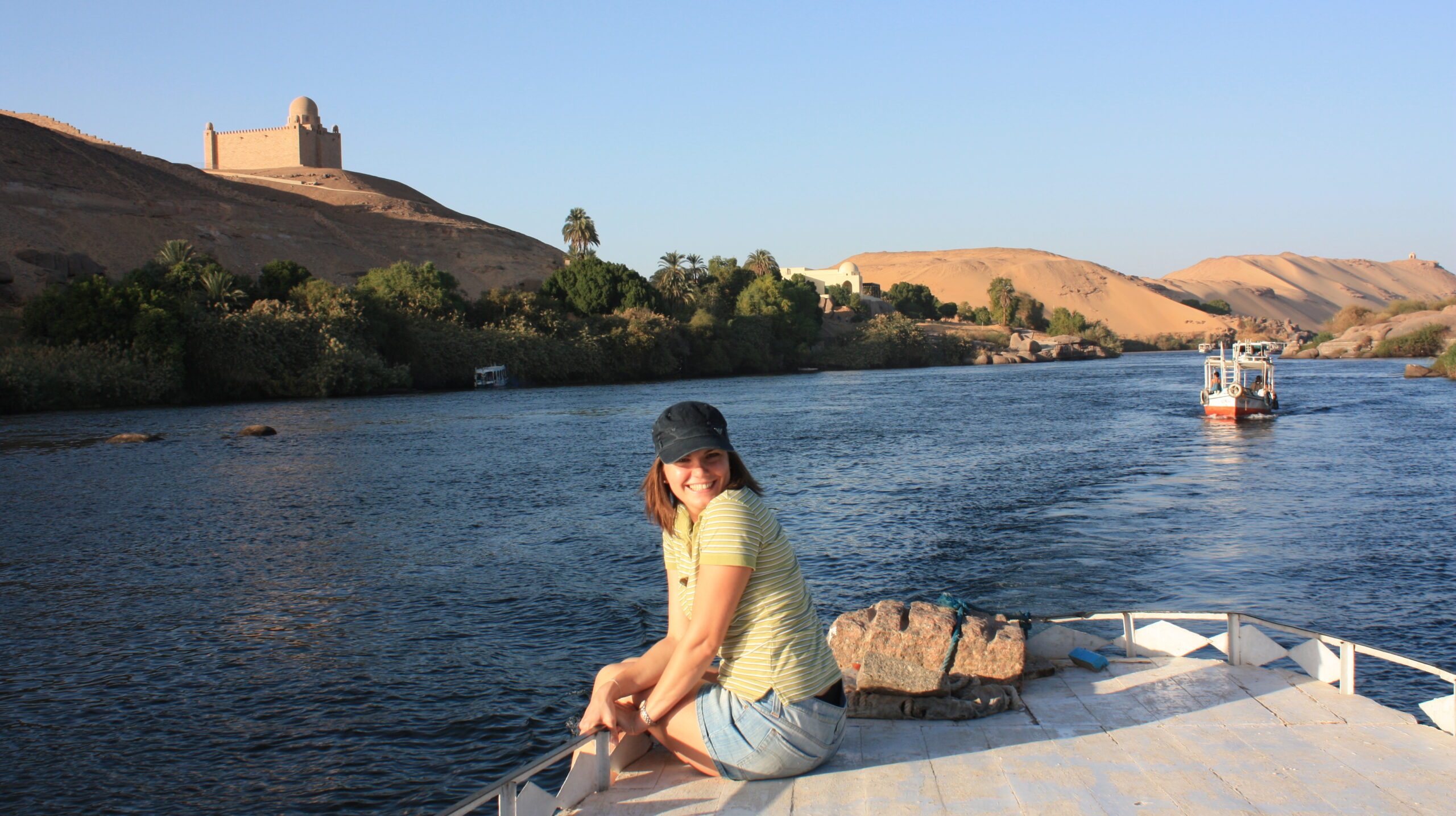rear-view-woman-sitting-by-sea-against-clear-sky-sunset