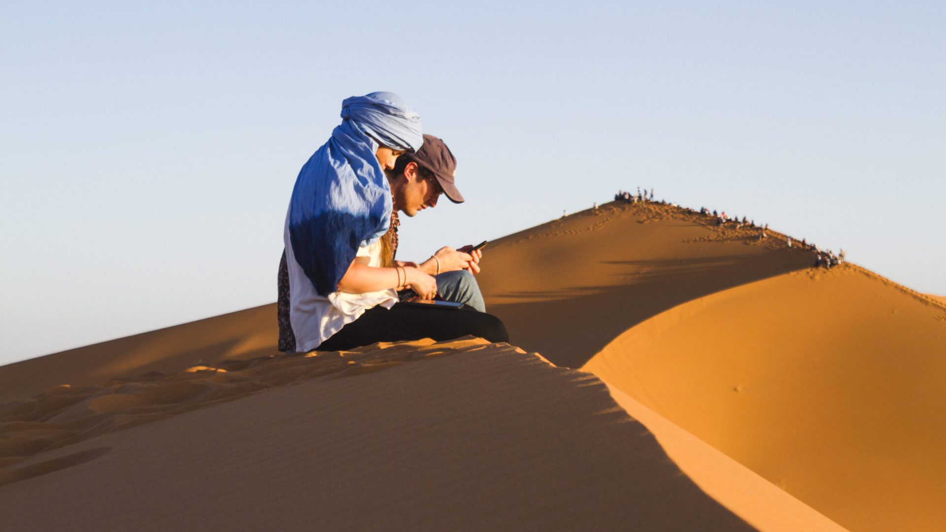 sideview-two-people-sitting-dune (1)