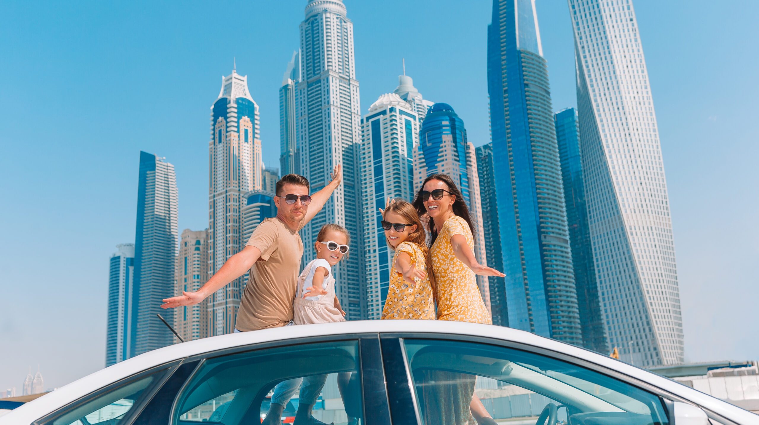 Family summer vacation. Family of four on car vacation on background of skyscrapers in Dubai