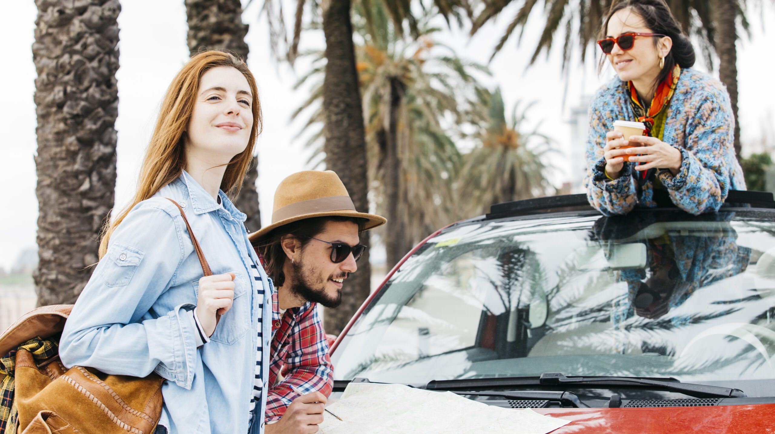 three-people-standing-near-car-with-road-map
