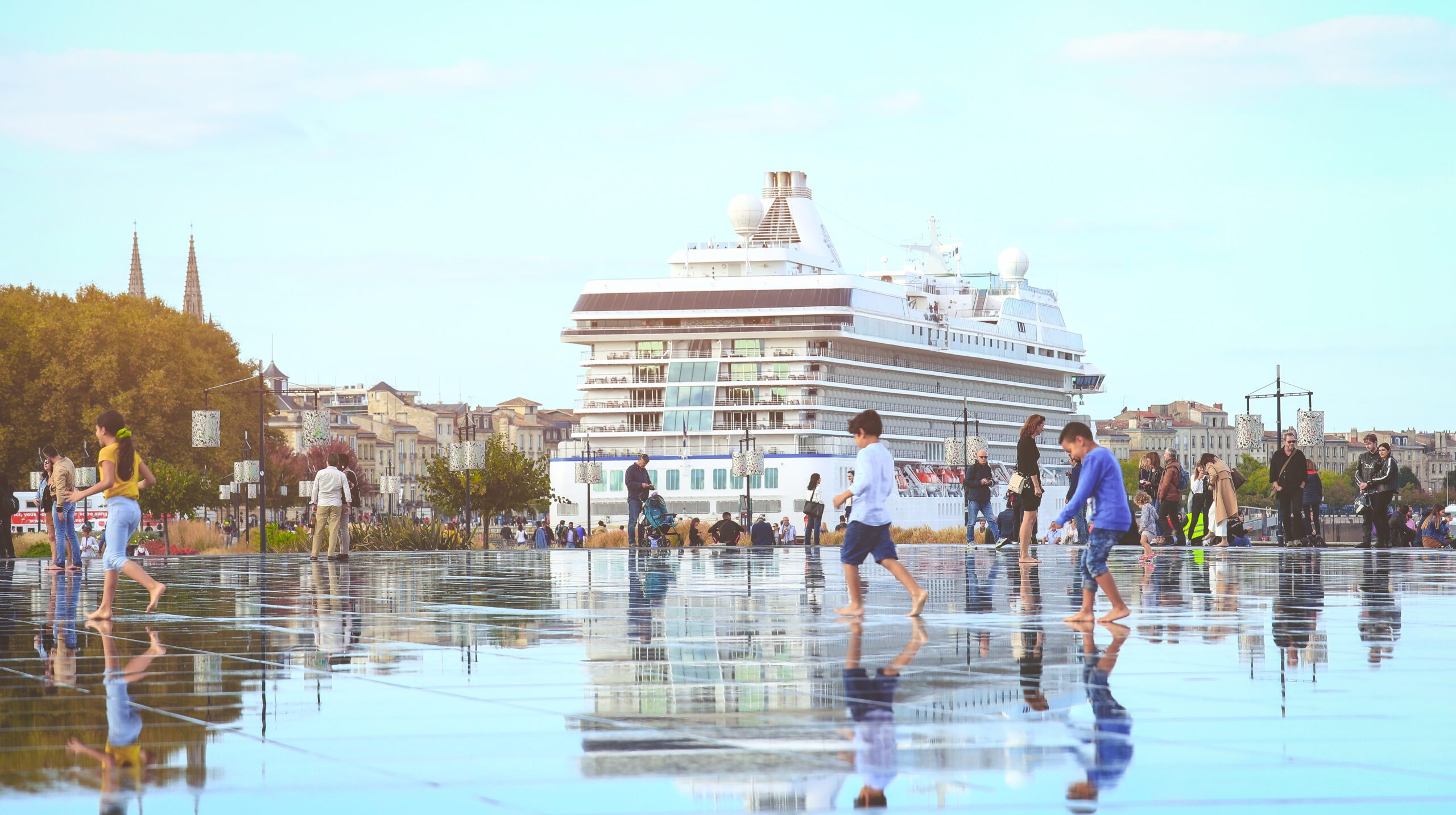 FRANCE, BORDEAUX - SEPTEMBER 29, 2018 : Selective focus on tourists enjoy walking on Bordeaux water mirorr with famous dutch cruise ship on the back