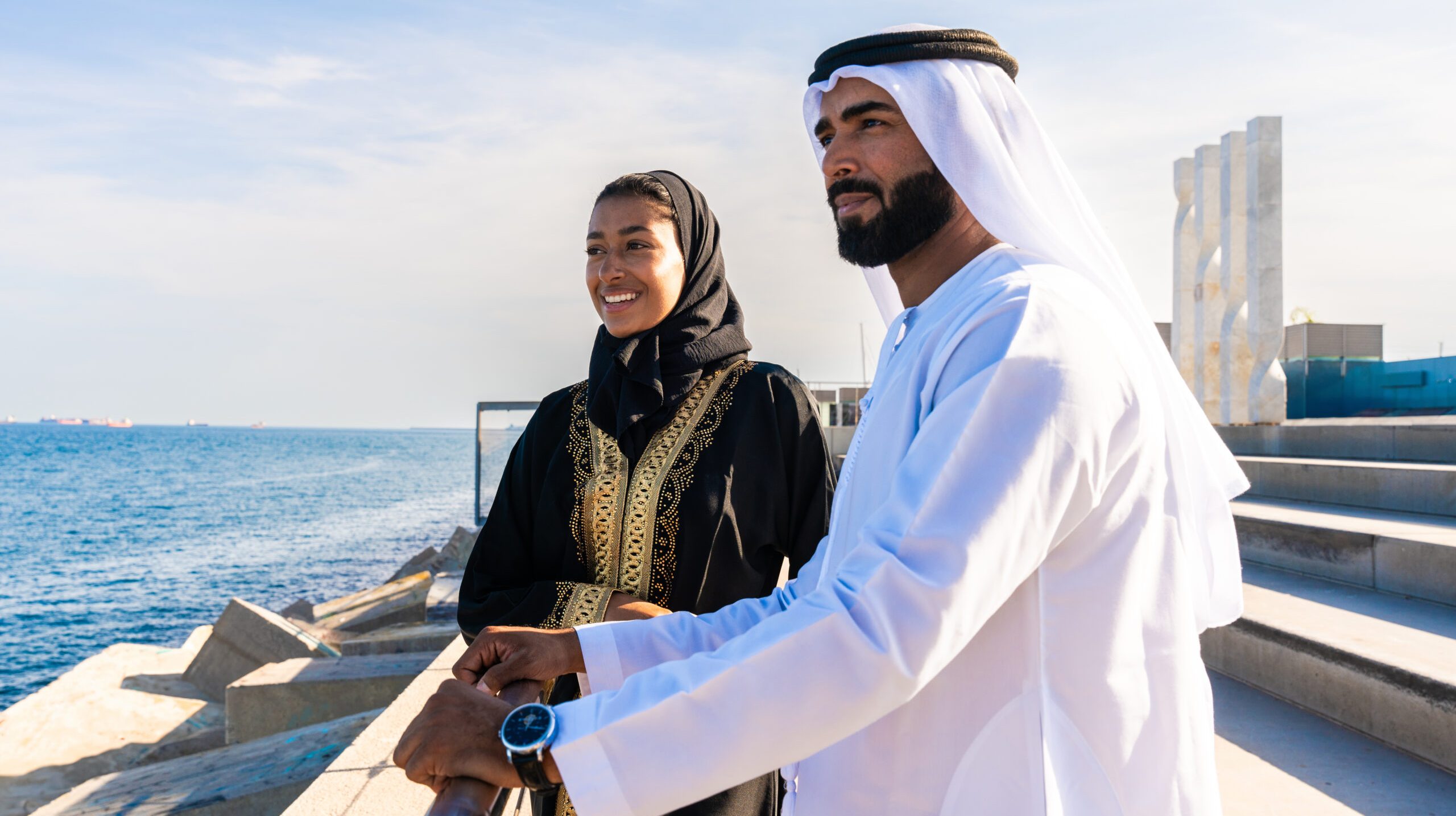 Traditional arab couple wearing emirati clothing dating outdoors - Middle-eastern married woman with abaya and man with kandura meeting and having fun in the city