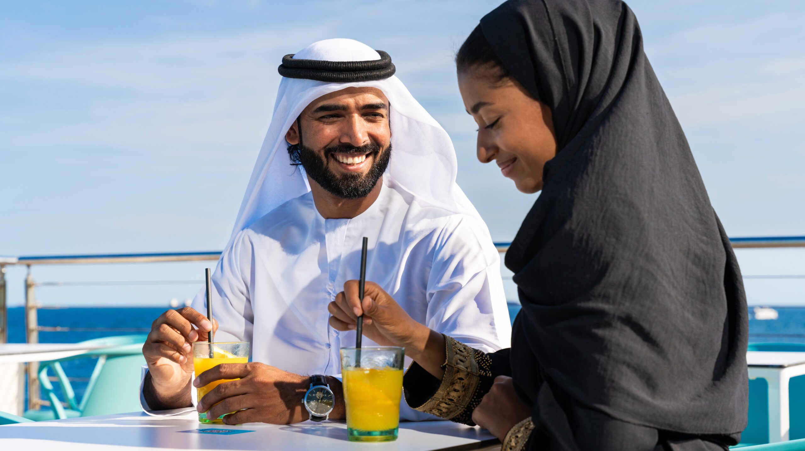 Traditional arab couple wearing emirati clothing dating outdoors - Middle-eastern married woman with abaya and man with kandura meeting and having fun in the city