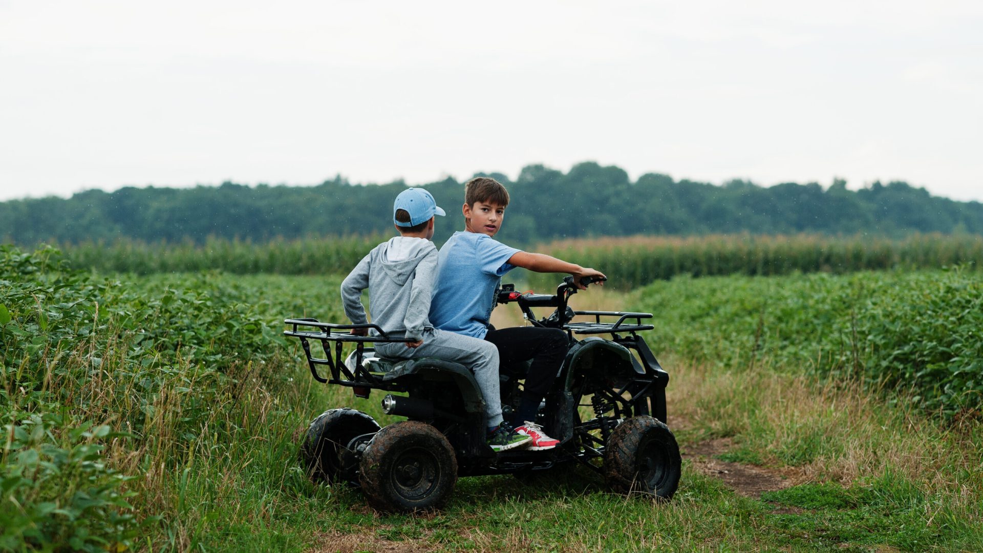 Two brothers driving four-wheller ATV quad bike. Happy children moments.