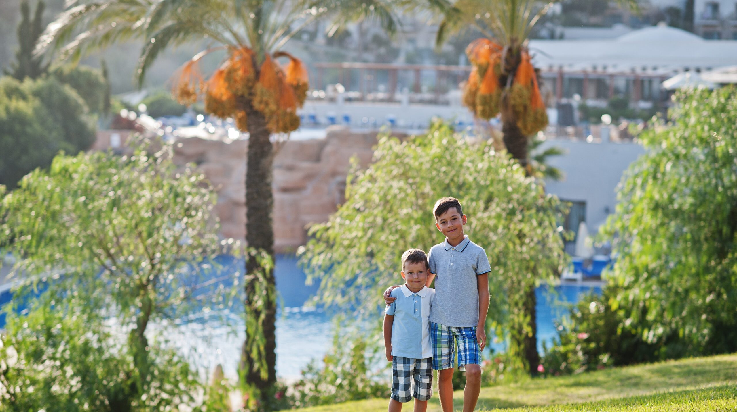 Two brothers on Turkey resort against palms.