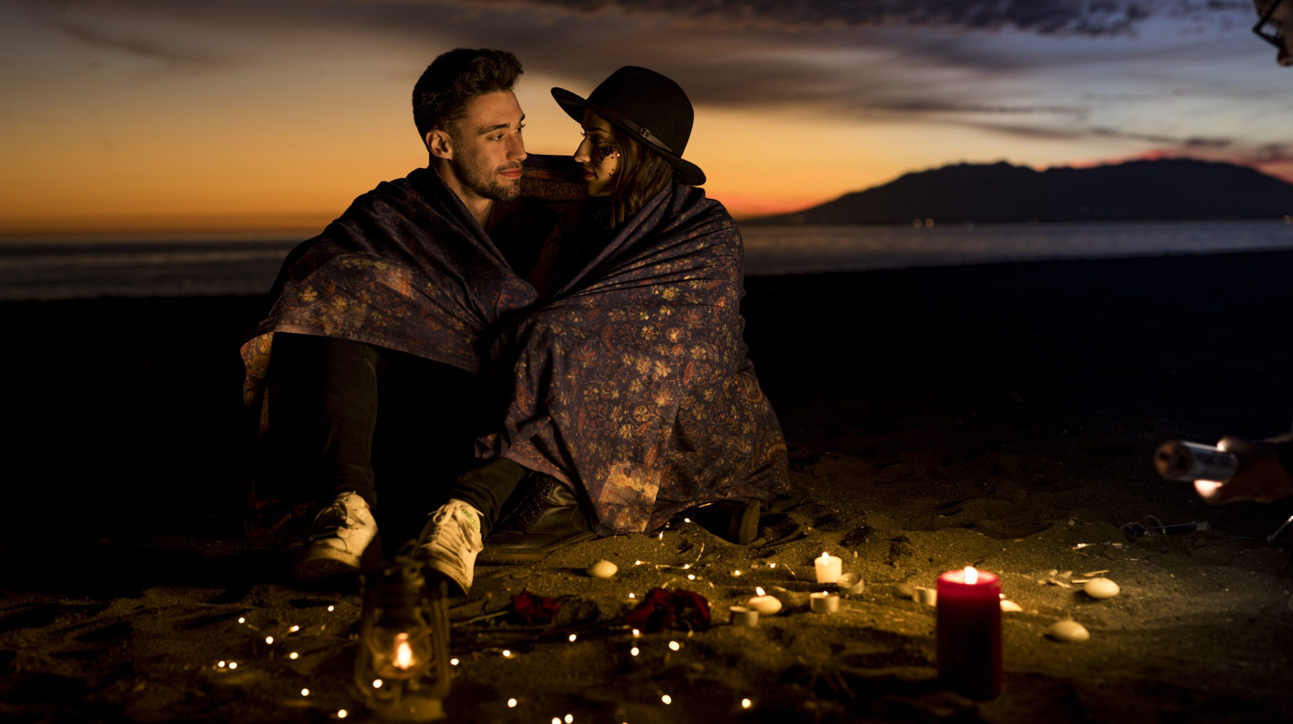 young-couple-blanket-sitting-sea-shore